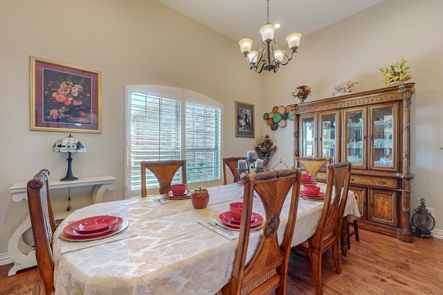 dining area featuring an inviting chandelier, vaulted ceiling, and hardwood / wood-style flooring