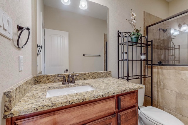 bathroom featuring vanity, a shower with shower door, and toilet