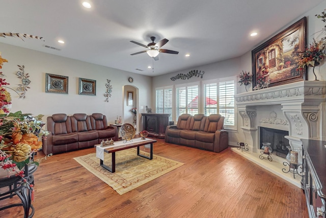 living room with a fireplace, ceiling fan, and light hardwood / wood-style flooring