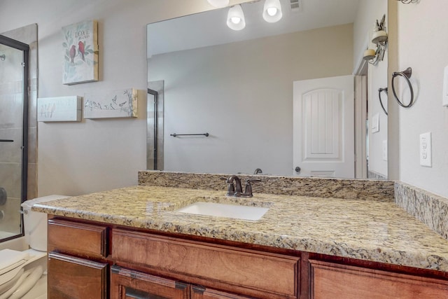 bathroom featuring a shower with shower door, vanity, and toilet