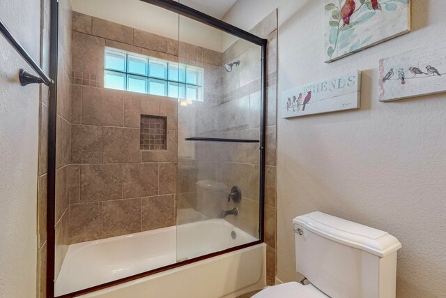 bathroom featuring shower / bath combination with glass door and toilet