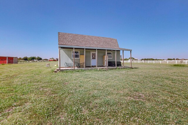 view of front of house featuring an outdoor structure, a front yard, and a rural view