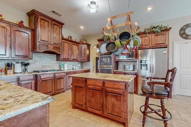 kitchen with appliances with stainless steel finishes, a center island, light tile patterned floors, and tasteful backsplash