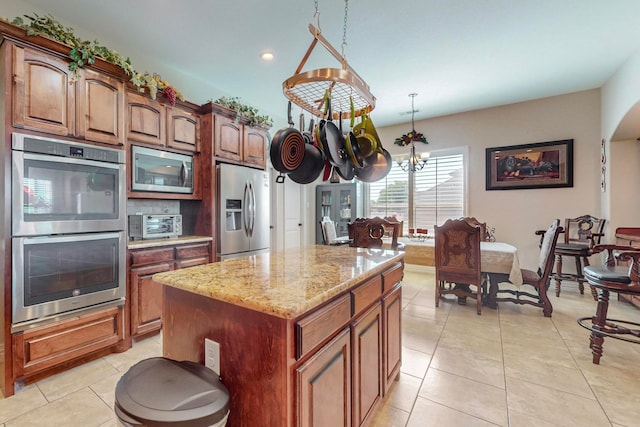 kitchen featuring light tile patterned floors, stainless steel appliances, decorative light fixtures, and a kitchen island