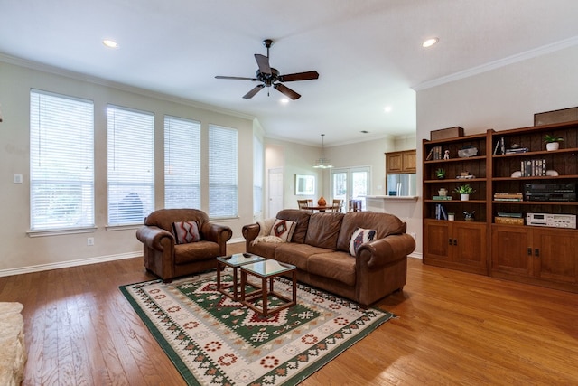 living room with hardwood / wood-style flooring, ceiling fan with notable chandelier, and crown molding