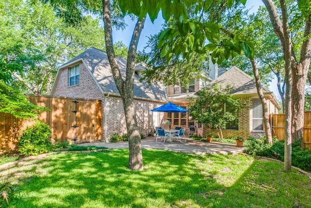 rear view of house featuring a lawn and a patio