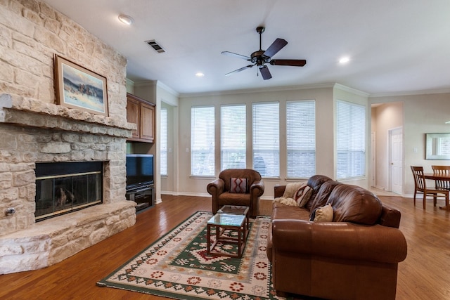 living room featuring ceiling fan, a fireplace, crown molding, and hardwood / wood-style floors