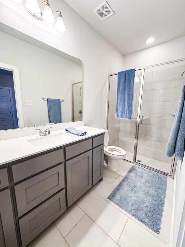 bathroom featuring vanity, toilet, a shower with shower door, and tile patterned flooring