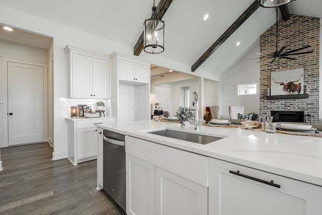 kitchen featuring lofted ceiling with beams, white cabinetry, light stone counters, and sink