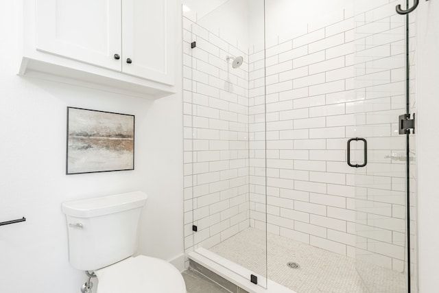 bathroom with a shower with shower door and toilet