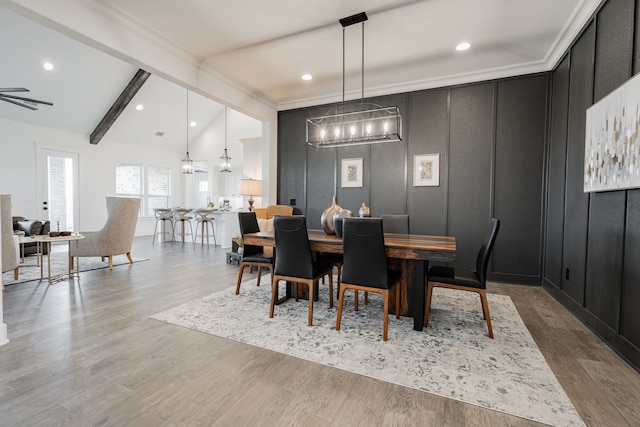 dining space with wood-type flooring, ceiling fan with notable chandelier, lofted ceiling with beams, and crown molding