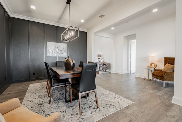 dining space with ornamental molding, a chandelier, and hardwood / wood-style floors