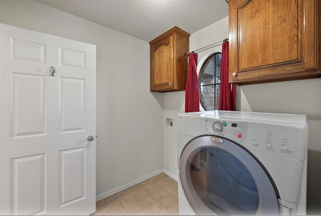 clothes washing area with a textured ceiling, washer / clothes dryer, light tile patterned floors, and cabinets