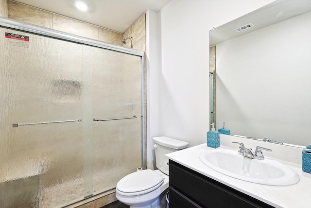 bathroom featuring vanity, a shower with shower door, and toilet