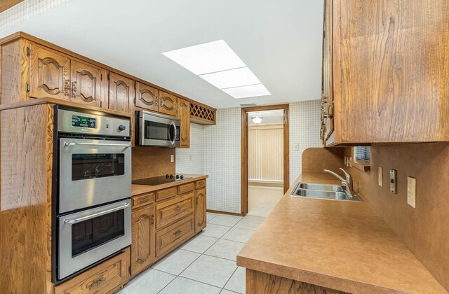 kitchen featuring appliances with stainless steel finishes, light tile patterned flooring, and sink