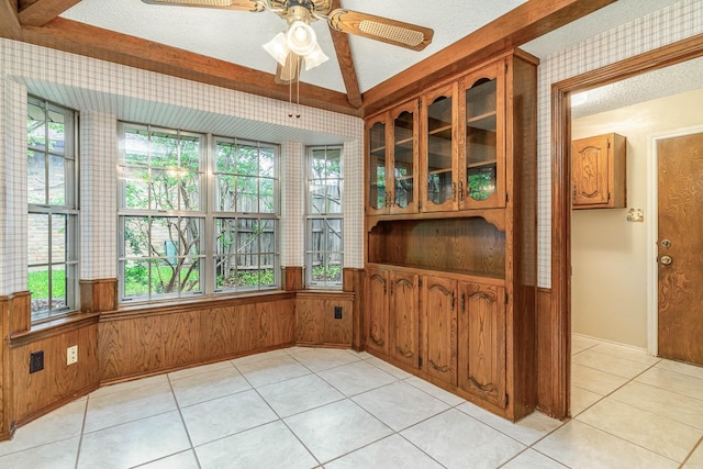 dining area with light tile patterned floors, wooden walls, a textured ceiling, and ceiling fan