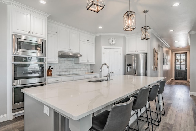 kitchen featuring crown molding, a sink, appliances with stainless steel finishes, baseboards, and under cabinet range hood