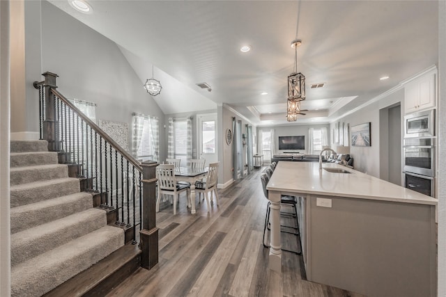 kitchen with a sink, stainless steel microwave, a healthy amount of sunlight, open floor plan, and dark wood-type flooring