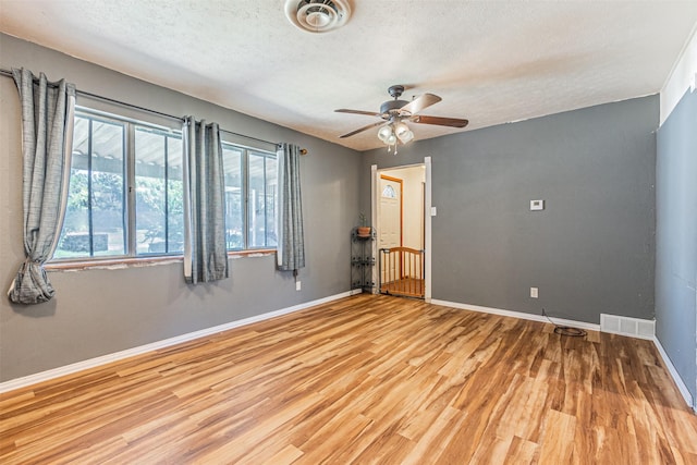 spare room with ceiling fan, a textured ceiling, and light hardwood / wood-style floors