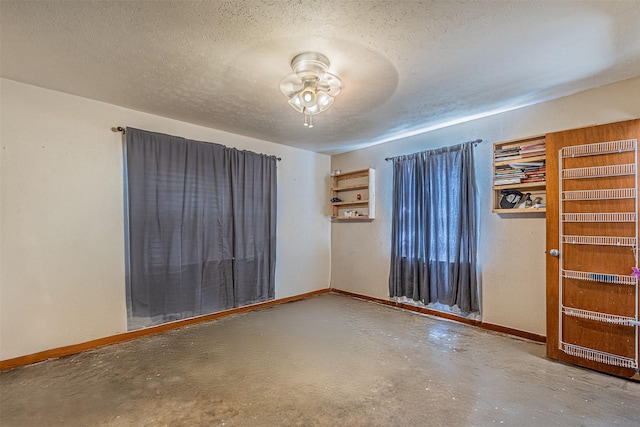 spare room featuring a textured ceiling, ceiling fan, and concrete floors