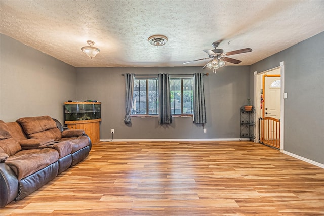 living room featuring ceiling fan, a textured ceiling, and light hardwood / wood-style flooring