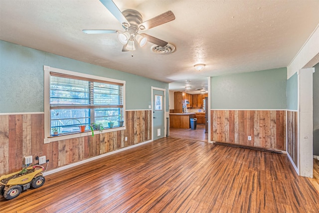 empty room featuring a textured ceiling, ceiling fan, and wood-type flooring