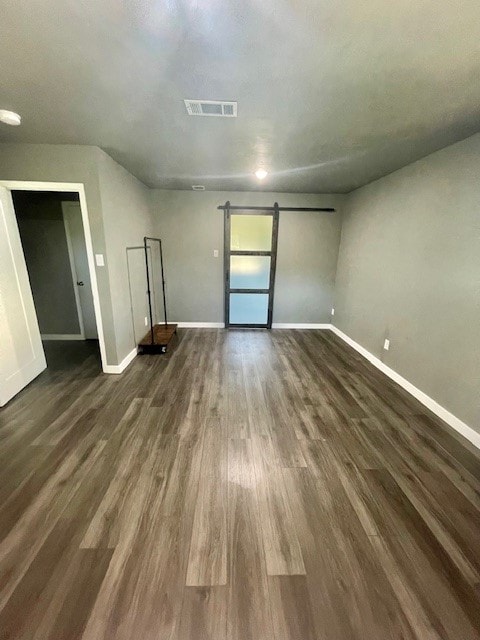 unfurnished living room with a barn door and dark hardwood / wood-style floors