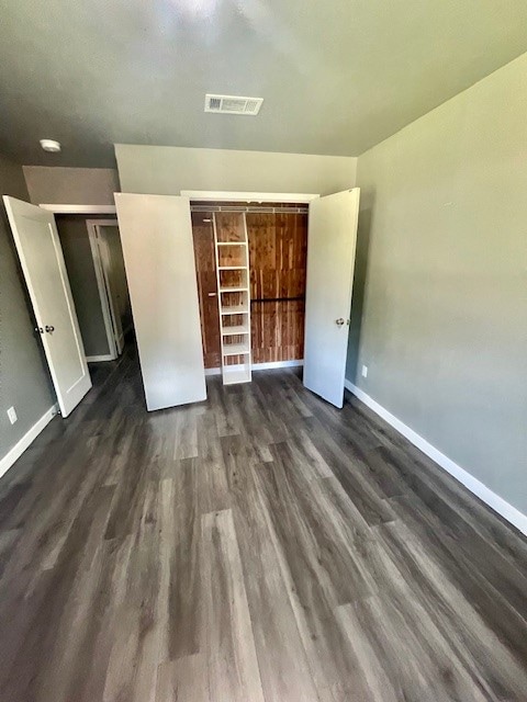 unfurnished bedroom featuring a closet and dark hardwood / wood-style flooring