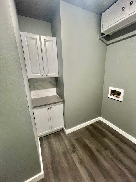 laundry room with washer hookup, dark wood-type flooring, and cabinets