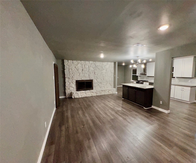 unfurnished living room with hardwood / wood-style floors, a notable chandelier, and a stone fireplace