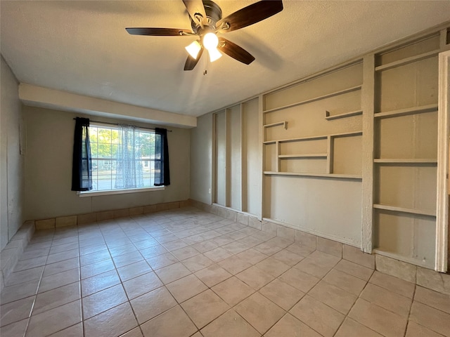 spare room with a textured ceiling, ceiling fan, and light tile patterned floors