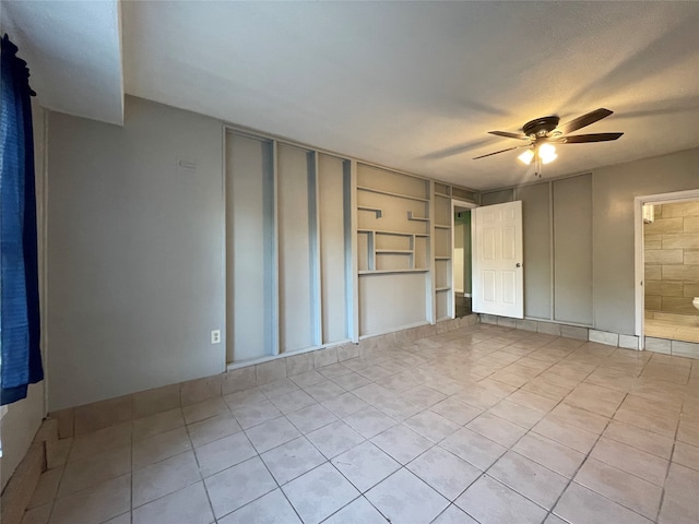 tiled spare room featuring a textured ceiling and ceiling fan