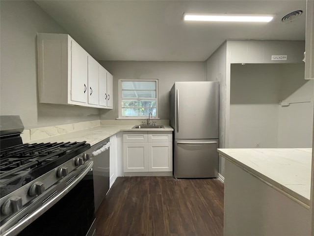 kitchen with appliances with stainless steel finishes, sink, dark hardwood / wood-style floors, and white cabinets