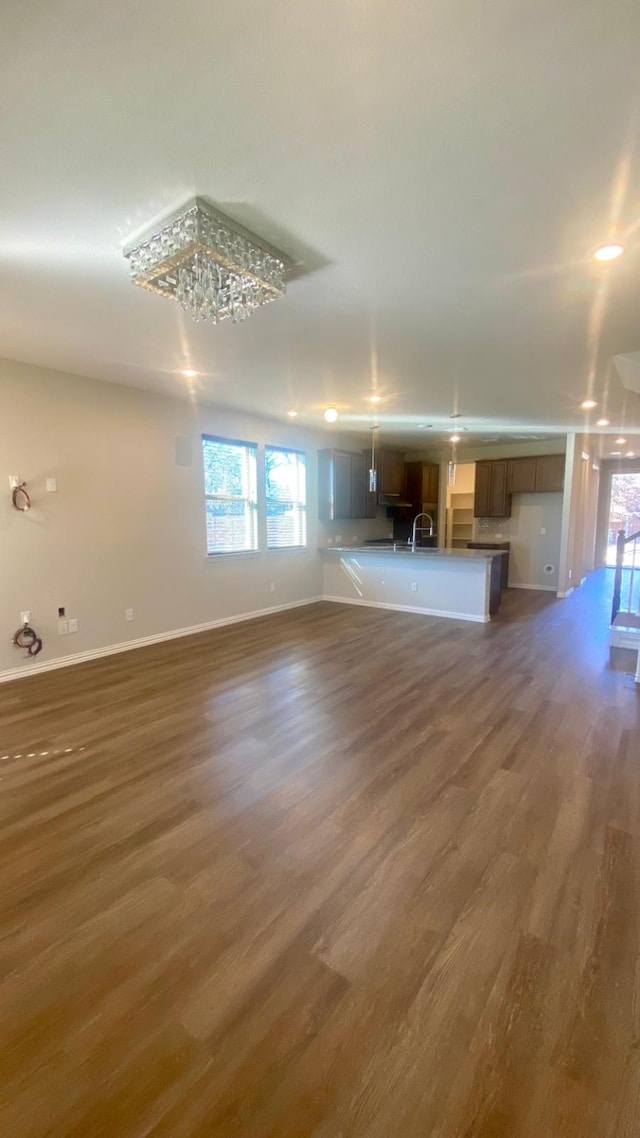 unfurnished living room featuring plenty of natural light, a chandelier, and dark hardwood / wood-style floors