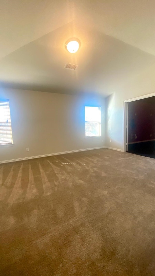 carpeted spare room with vaulted ceiling and a healthy amount of sunlight