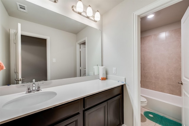 full bathroom featuring tile patterned floors, vanity, tiled shower / bath combo, and toilet