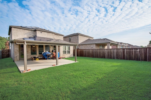 back of house with solar panels, a yard, and a patio