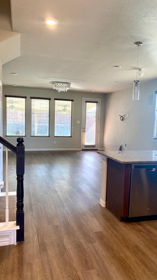 interior space with light stone countertops, dishwasher, hanging light fixtures, an inviting chandelier, and dark hardwood / wood-style floors