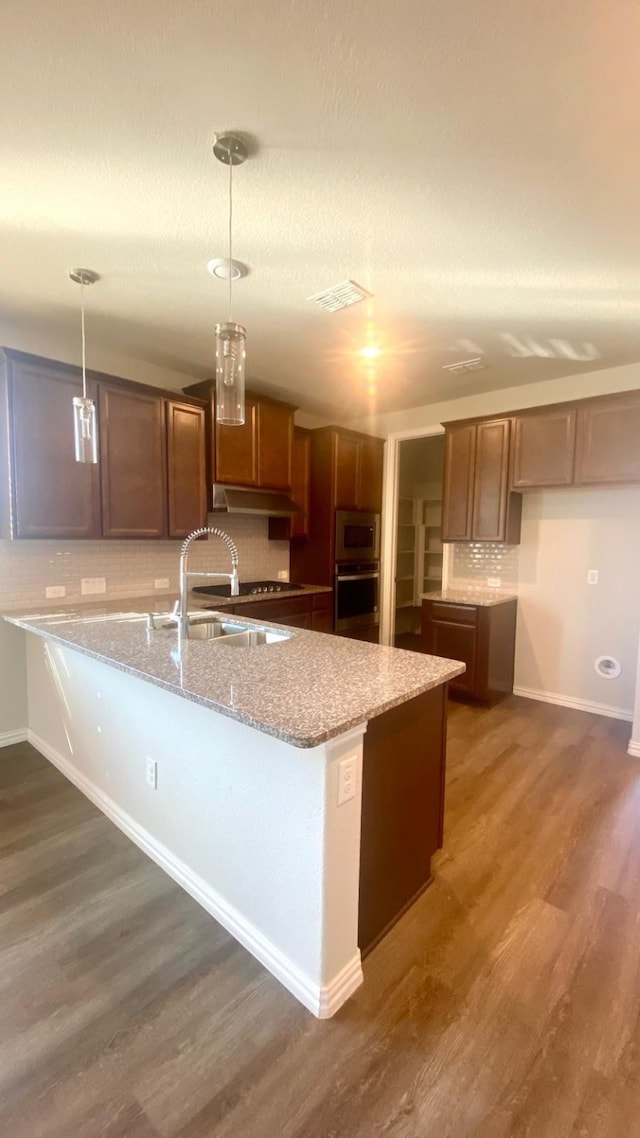 kitchen featuring sink, stainless steel appliances, dark hardwood / wood-style floors, pendant lighting, and decorative backsplash