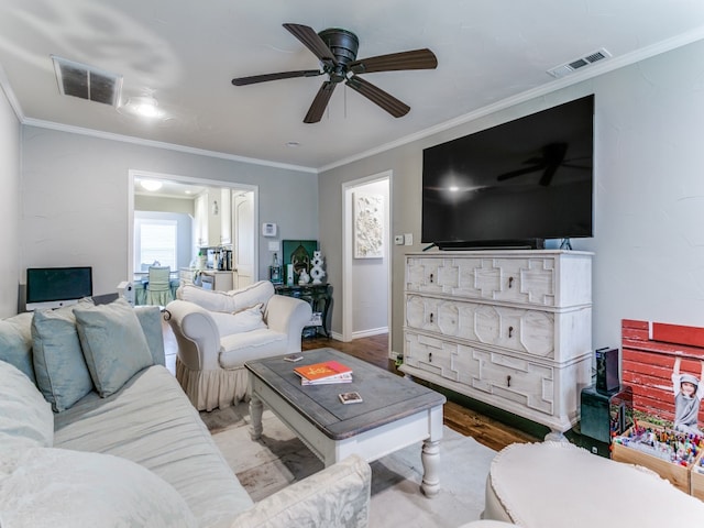 living room featuring ceiling fan, light wood-type flooring, and crown molding