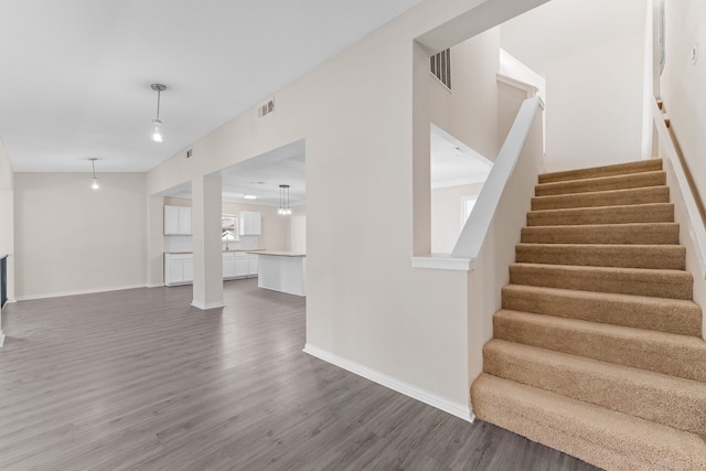 kitchen with sink, pendant lighting, a center island, white cabinets, and light wood-type flooring