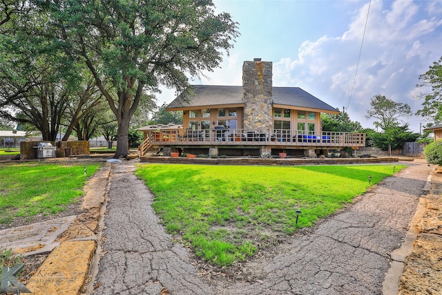 rear view of house with a yard, a chimney, and a wooden deck