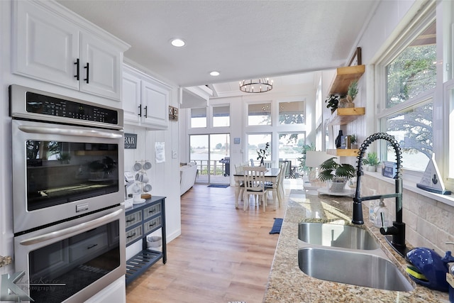 kitchen featuring double oven, light hardwood / wood-style flooring, white cabinetry, and a wealth of natural light