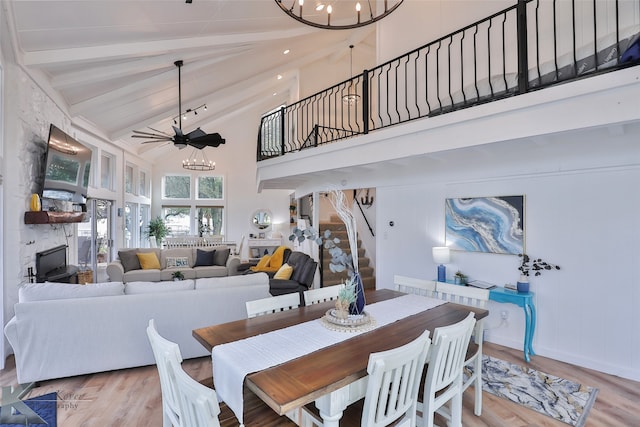 dining area featuring ceiling fan with notable chandelier, beam ceiling, light hardwood / wood-style flooring, and high vaulted ceiling