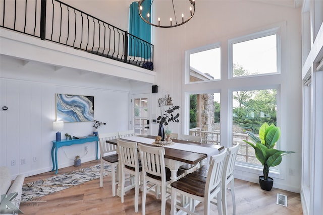 dining area featuring a notable chandelier, a high ceiling, and light wood-type flooring