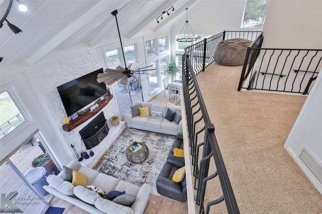 carpeted living room with beamed ceiling, ceiling fan with notable chandelier, plenty of natural light, and high vaulted ceiling