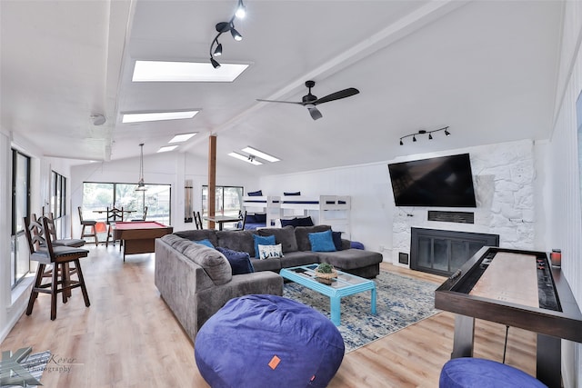 living room featuring a fireplace, lofted ceiling with beams, light hardwood / wood-style floors, and pool table