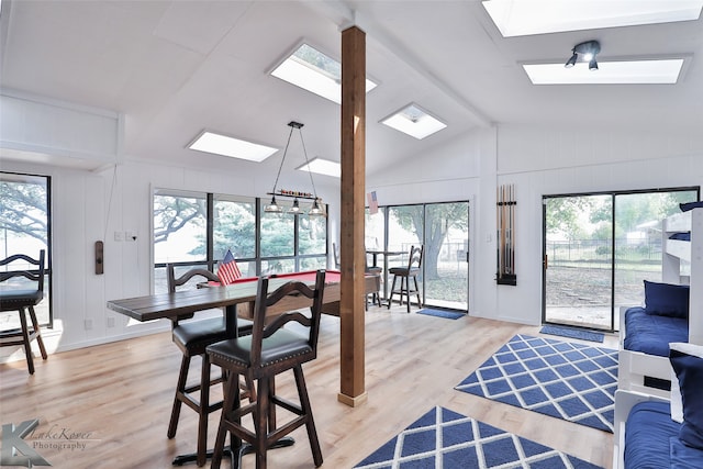 dining space featuring light wood-type flooring and lofted ceiling with skylight