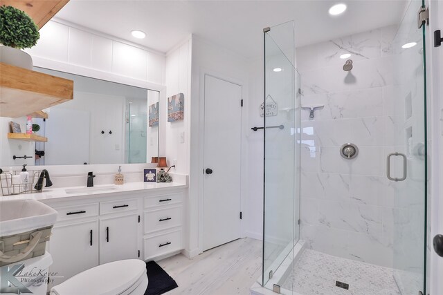 bathroom with wood-type flooring, vanity, toilet, and an enclosed shower