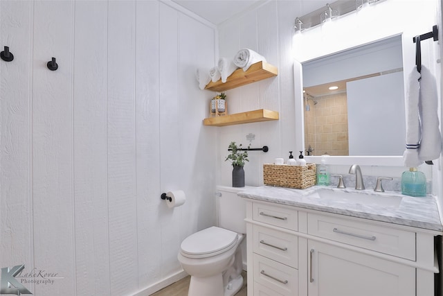 bathroom featuring a tile shower, vanity, and toilet